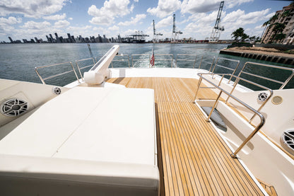 Upper aft deck with a large white sunpad, teak walkway, and stainless-steel rails