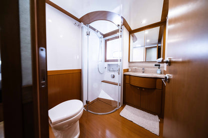 Yacht bathroom with a glass shower enclosure, curved sink vanity, and wood trim